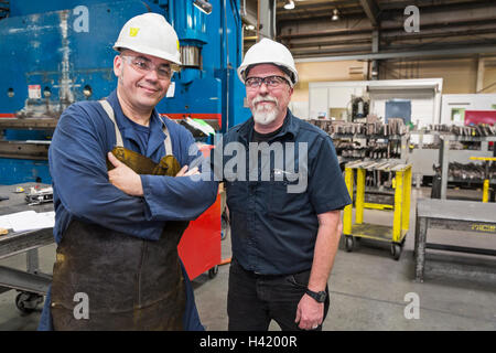 Smiling workers posing in factory Stock Photo