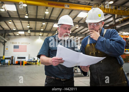 Workers examining paperwork in factory Stock Photo