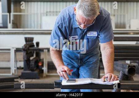Caucasian worker using calculator in factory Stock Photo
