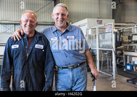 Smiling Caucasian workers posing in factory Stock Photo