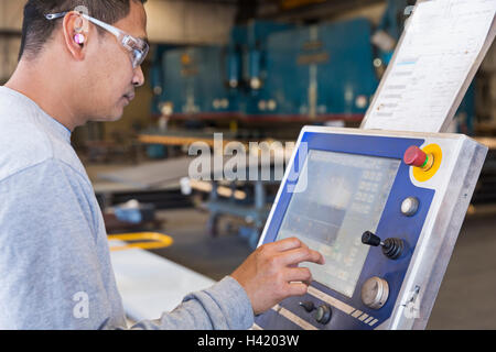 Asian worker using control panel in factory Stock Photo
