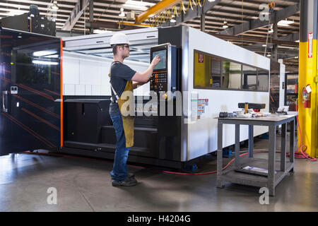 Caucasian worker using control panel in factory Stock Photo