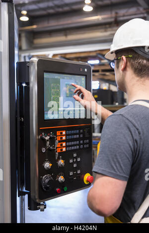 Caucasian worker using control panel in factory Stock Photo