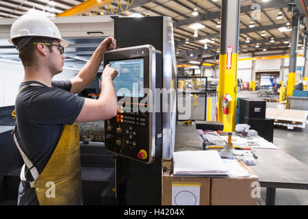 Caucasian worker using control panel in factory Stock Photo