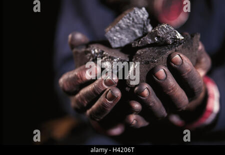 Hands holding lumps of coal Stock Photo