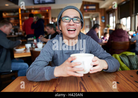 Laughing Asian man in coffee shop Stock Photo