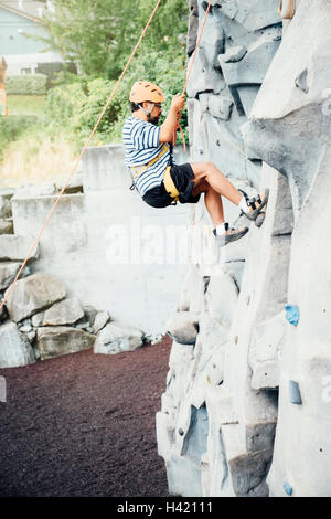 Mixed Race man climbing rock climbing wall Stock Photo