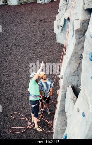 Woman and man looking up at rock climbing wall Stock Photo