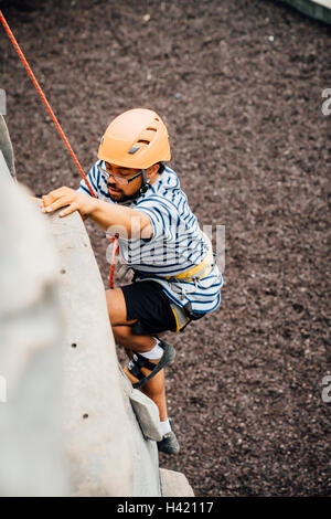 Mixed Race man climbing rock climbing wall Stock Photo