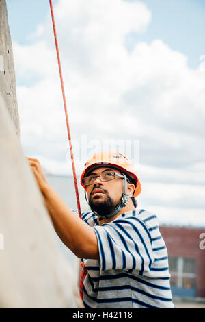 Mixed Race man climbing rock climbing wall Stock Photo