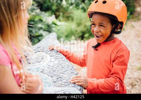 Smiling boy wearing helmet talking to girl on bench Stock Photo