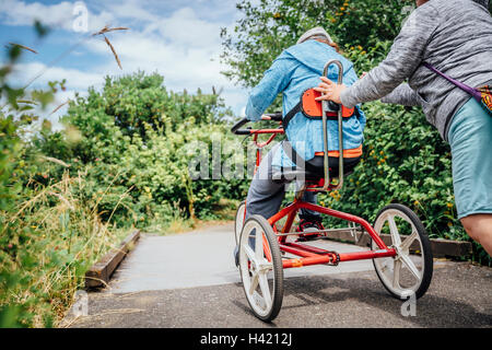 Caucasian woman pushing daughter riding tricycle Stock Photo