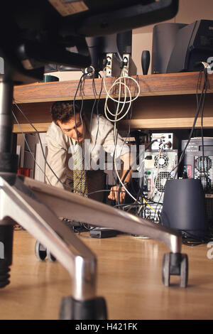 Office, desk, computer, man, kneel, check connections, cables, workplace, table, PC, monitor, connection, error, problem, defective, controls, check, check, problem solving, IT expert, expert, expert, computer expert, work, occupation, fault location, ins Stock Photo