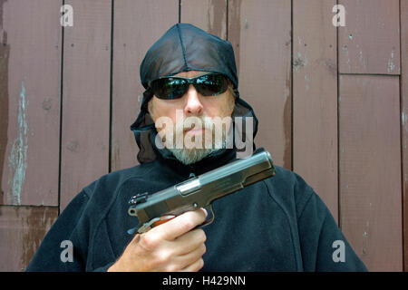A criminal gang member gangster robber or mugger pointing a colt 45 automatic pistol Stock Photo