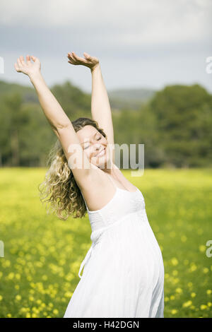 Woman, young, happy, pregnant, arms rised, side view, flower meadow, model released, Stock Photo