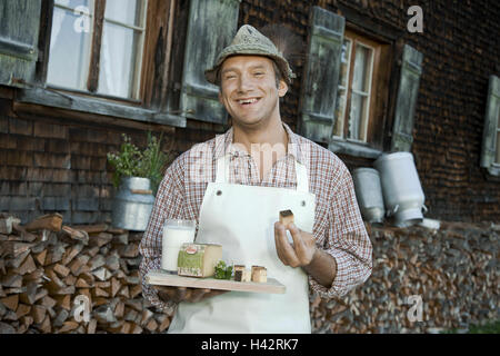 Austria, Vorarlberg, Bödele, Alpine dairyman, looking at camera, smiling, holding snack plate, Stock Photo