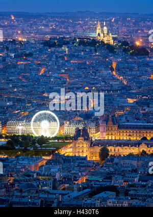 Aerial view of Paris rooftops at dusk, including The Louvre, and Sacre Coeur in Montmartre. Blue hour in the City of Light