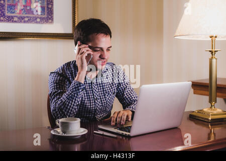 Business man connecting cell phone and computer wireless in office Stock Photo