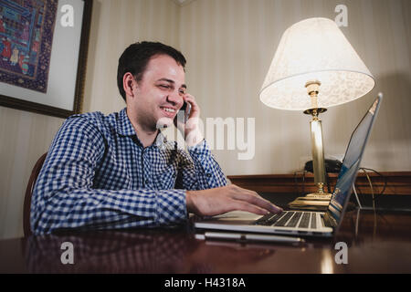 Young happy man talking on the phone at his workplace in office Stock Photo