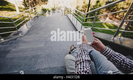 young Man with the phone in his hand sitting on the steps. top view Stock Photo