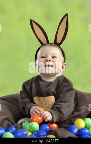 Infant, boy, lining, Easter bunny, Easter eggs, brightly, artificially, play, 1 year, child, smile, headgear, "hare's ears", costume, panels, lining, hare's costume, childhood, lighthearted, laugh, happy, cheerfulness, eggs, plastic eggs, loses, Easter, c Stock Photo