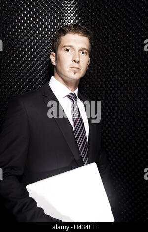 Businessman, rigidly, stand, laptop, carry, half portrait, model released, people, man's portrait, suit, jacket, shirt, tie, expression, seriously, inside, black, business, computer, bases, Stock Photo