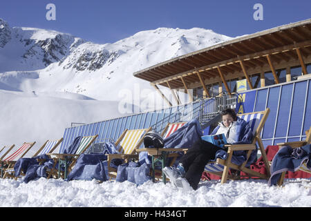 Austria, Tyrol, Serfaus, skiing area, mountain restaurant, Masner, detail, deck chair, woman, book, read, no model release, alps, mountains, season, winter, snow, snow-covered, winter sports area, winter sports, skiing area, tourism, tourism, person, outside, restaurant, ski hut, building, architecture, skier, wooden construction, sun themselves, rest, break, Stock Photo