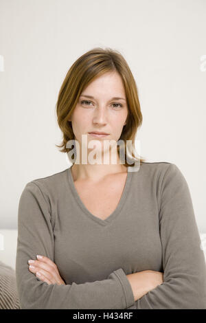 Woman, young, poor, annoyed, crosses semi-portrait bed people, 20-30 years, single, however self-confidently, furious, unsatisfied, challenging, stands, at home, interior, Stock Photo