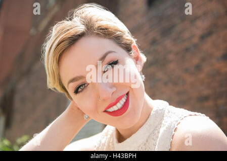 Caucasian woman smiling near brick wall Stock Photo