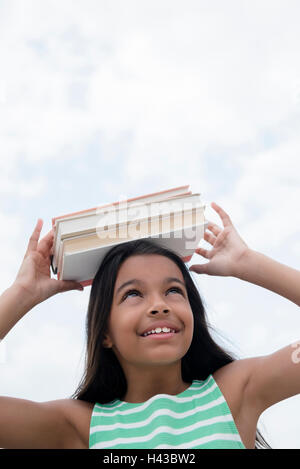 Mixed Race girl balancing books on head Stock Photo