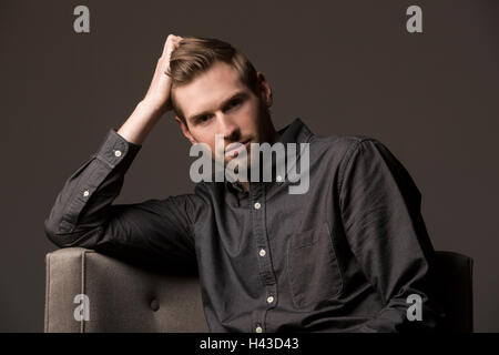 Serious Caucasian man with hand in hair Stock Photo