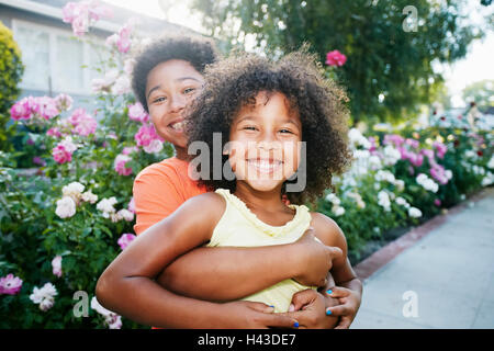 Mixed Race brother hugging sister outdoors Stock Photo