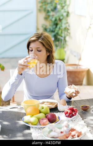 Woman, sit young, brunette, breakfast table, orange juice drink, model released, Stock Photo