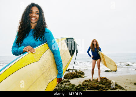 Smiling women holding surfboards at beach Stock Photo
