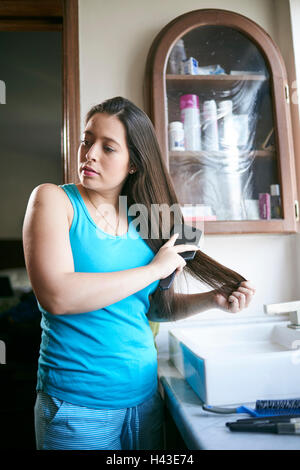 Hispanic woman wearing pajamas brushing hair Stock Photo