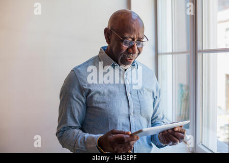 Man using digital tablet near window Stock Photo