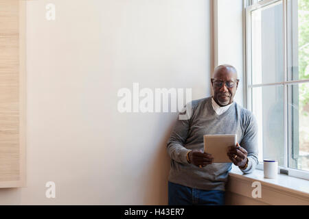 Man using digital tablet near window Stock Photo
