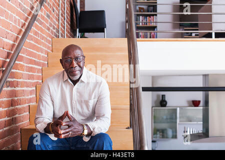 Smiling man sitting on staircase Stock Photo