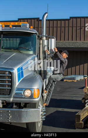 Caucasian man climbing into semi-truck Stock Photo