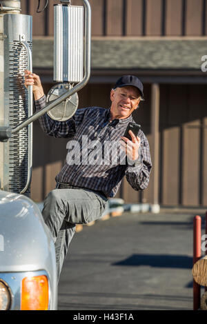 Caucasian man climbing into semi-truck texting on cell phone Stock Photo