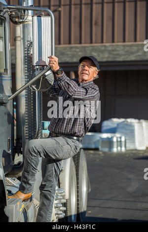 Caucasian man climbing into semi-truck Stock Photo
