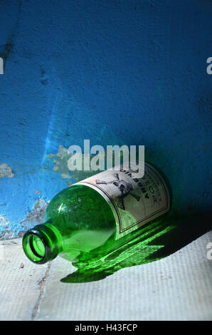 An old green glass  bottle labelled with arsenic poison and a skull and bone sign lies on the ground. Stock Photo