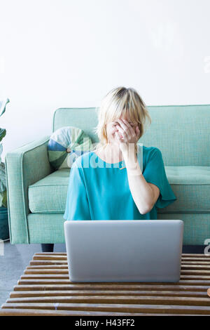 Laughing Caucasian woman sitting on floor using laptop Stock Photo