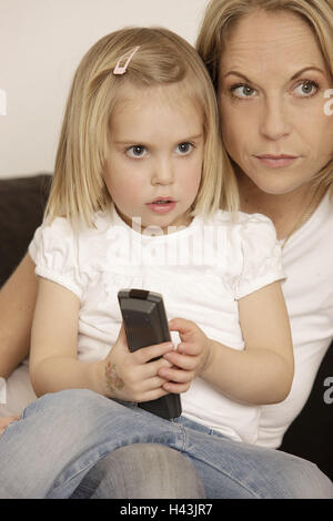 Nut, subsidiary, sofa, sit, hold television looking, portrait, curled, model released, people, child, woman, blond, lap, remote control, view, excommunicated, excitingly, concentration, Stock Photo