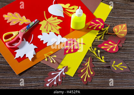 Autumn colored paper leaves on the wooden background. The child