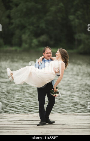 Groom carrying bride near lake and forest Stock Photo