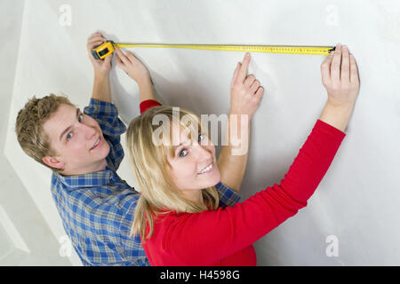 Couple, young, wall, tape measure, measure, icon, do it yourself, person, construction, men at work, build, DIY, do-it-yourselfers, tools, renovate, smile, measure, happy, tape measure, length, Stock Photo