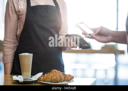 Man paying bill through smartphone using NFC technology Stock Photo