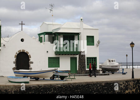 Spain, the Canaries, island Lanzarote, La Caleta de Famara, harbour, house, destination, volcano island, place, building, architecture, church, band, cross, ships, boots, people, passers-by, outside, Stock Photo