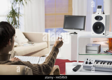Living room, man, young, gesture, long-distance-service, back view, no property release, series, people, screen, TVs, lcd-TV-set, loudspeakers, Mac mini, iPod video, Apple Remote, electronics, electro-appliances, technology, conversation, conversation-ele Stock Photo